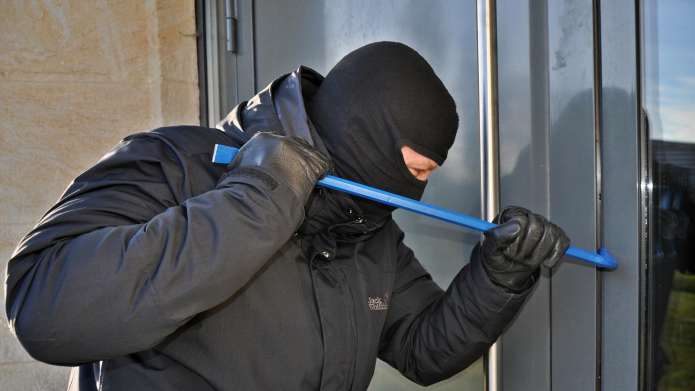 Afbeelding van een inbreker die met een koevoet een deur probeert te forceren